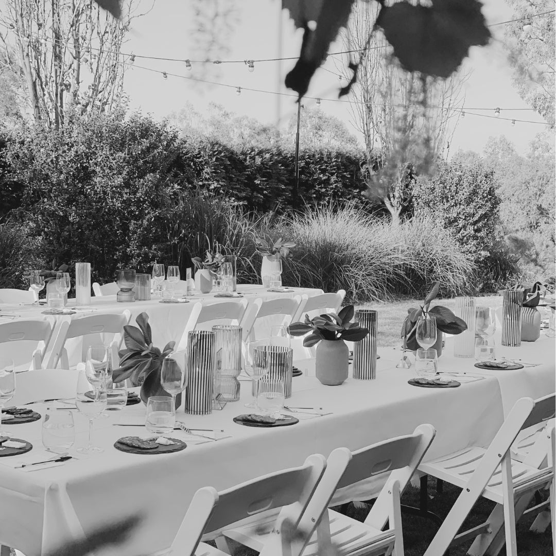 Outdoor setup for a Stay n’ Sip Fun Wine Tasting event with elegantly decorated tables, wine glasses, and greenery, creating a refined and inviting atmosphere for guests