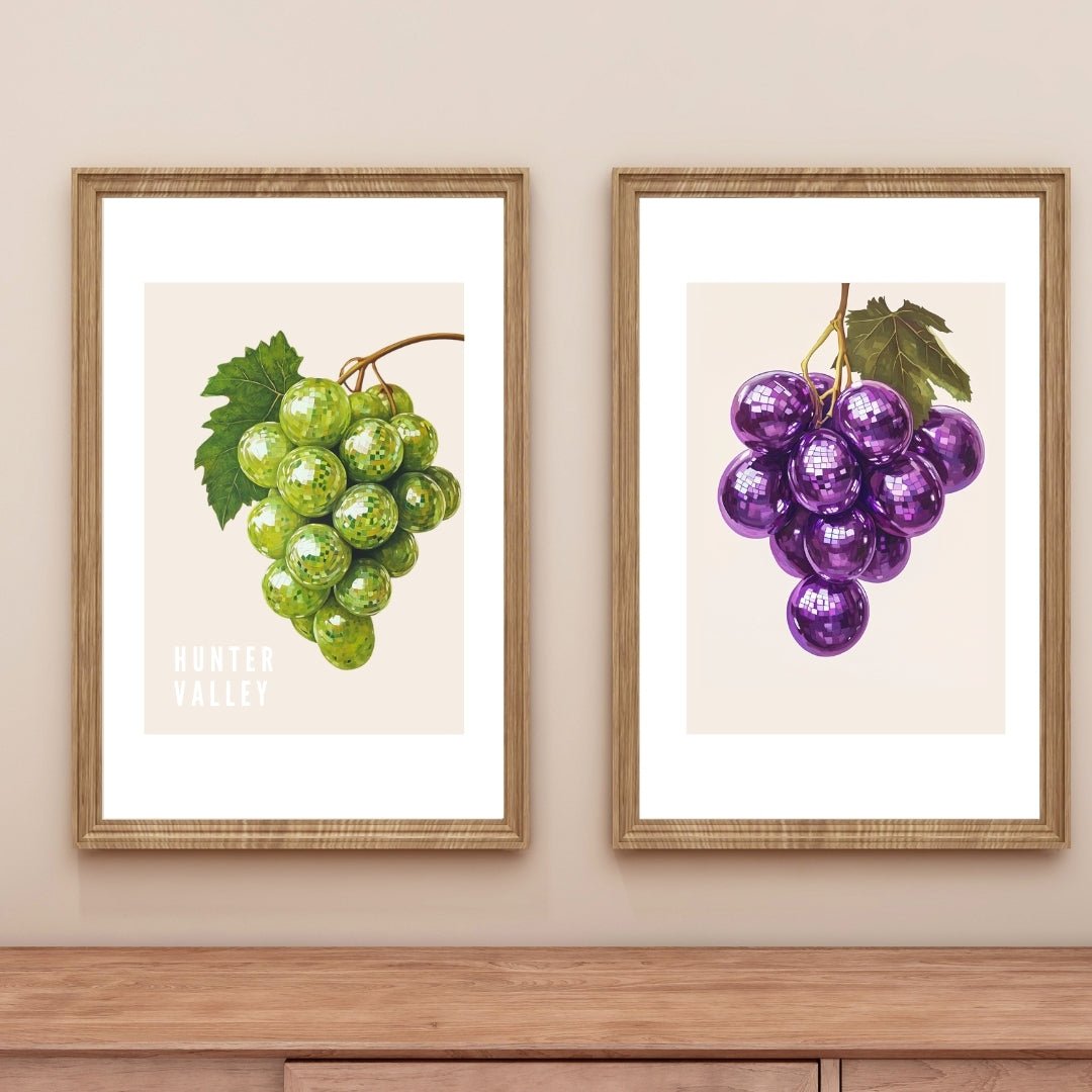 Framed Thirsty Merchy posters featuring green grapes with a shimmering effect and purple grapes with a disco-ball design, elegantly displayed on a neutral wall above a wooden console. These modern artworks celebrate Hunter Valley’s wine culture and are part of Stay n' Sip's exclusive collection, available for purchase online