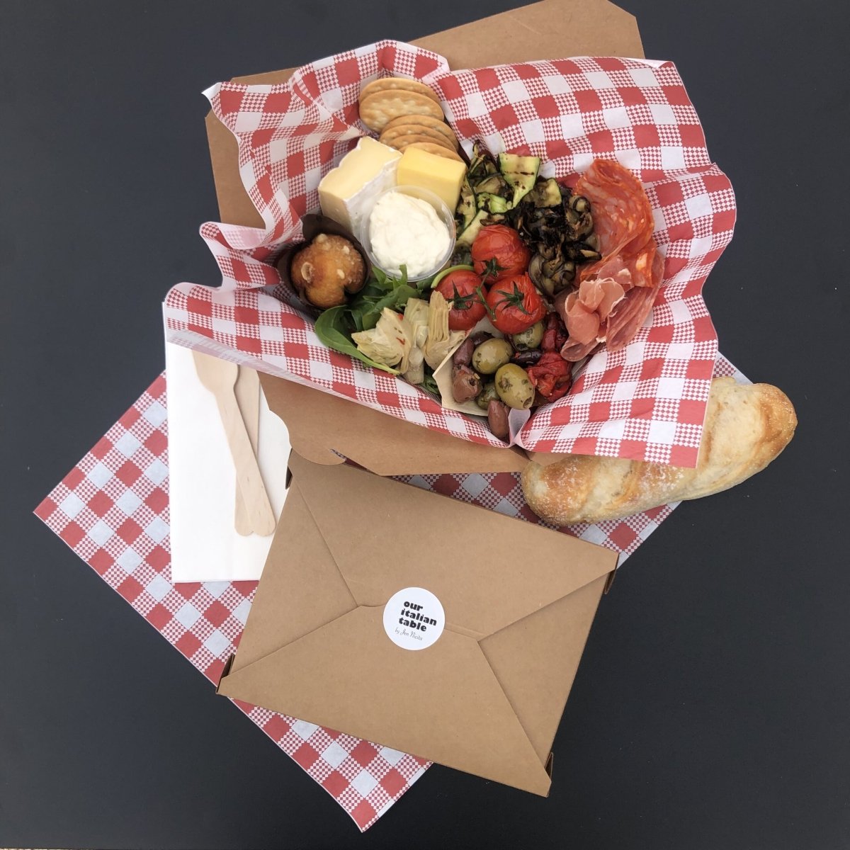 Gourmet antipasto individual box from Our Italian Table, featuring a selection of cheeses, cured meats, roasted vegetables, olives, and bread, perfect for enhancing the Stay n’ Sip wine tasting experience