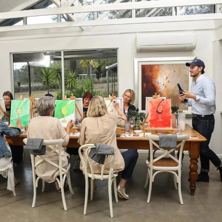 Group of women at Winmark Wines in Broke enjoying a Paint n Wine Tasting at a long table.