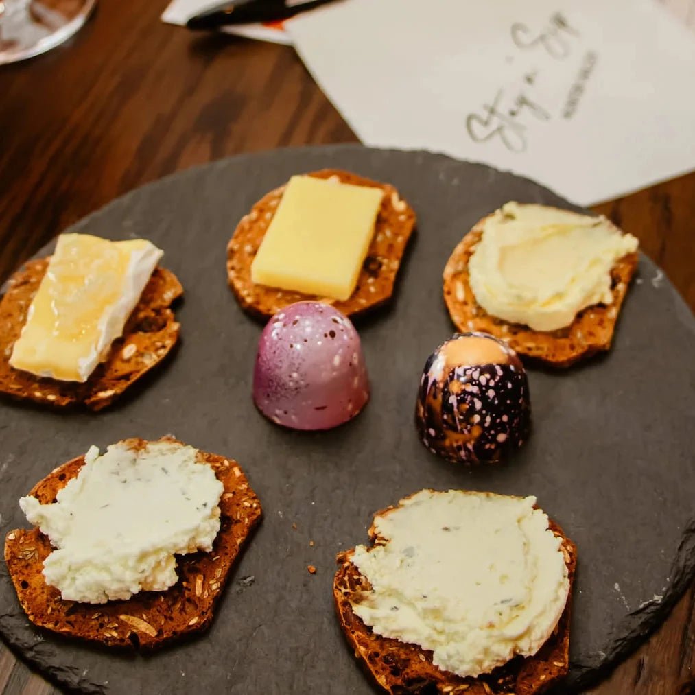 Plate with five crackers topped with cheese and two handmade chocolate bon bons.
