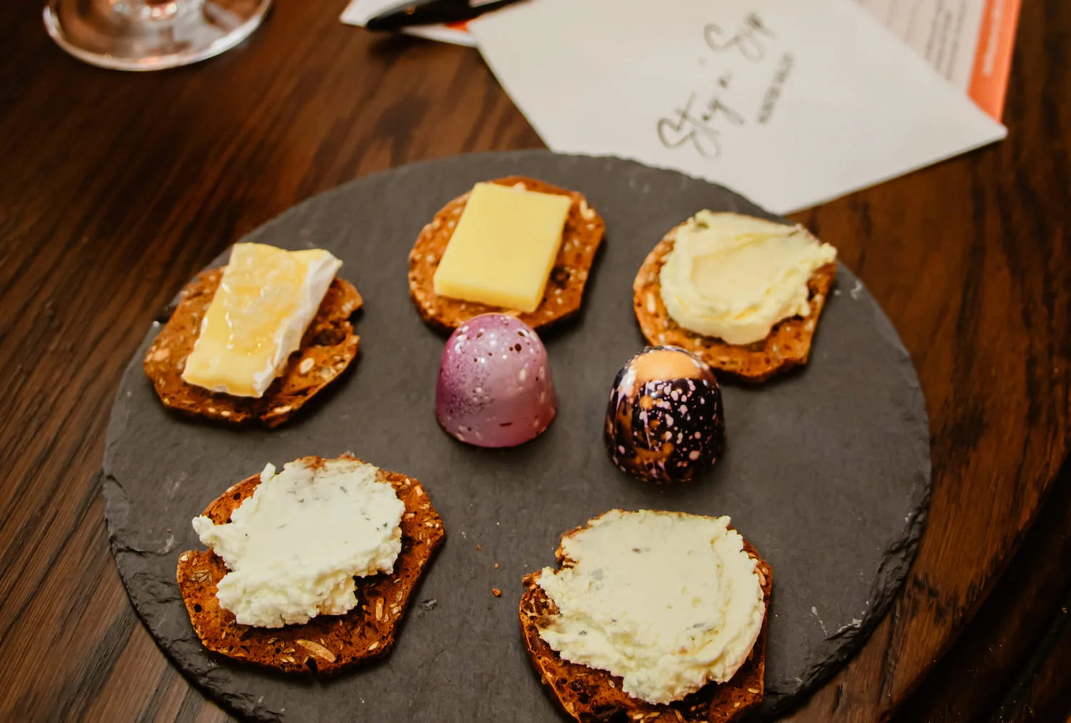 Plate with five crackers topped with cheese and two handmade chocolate bon bons.