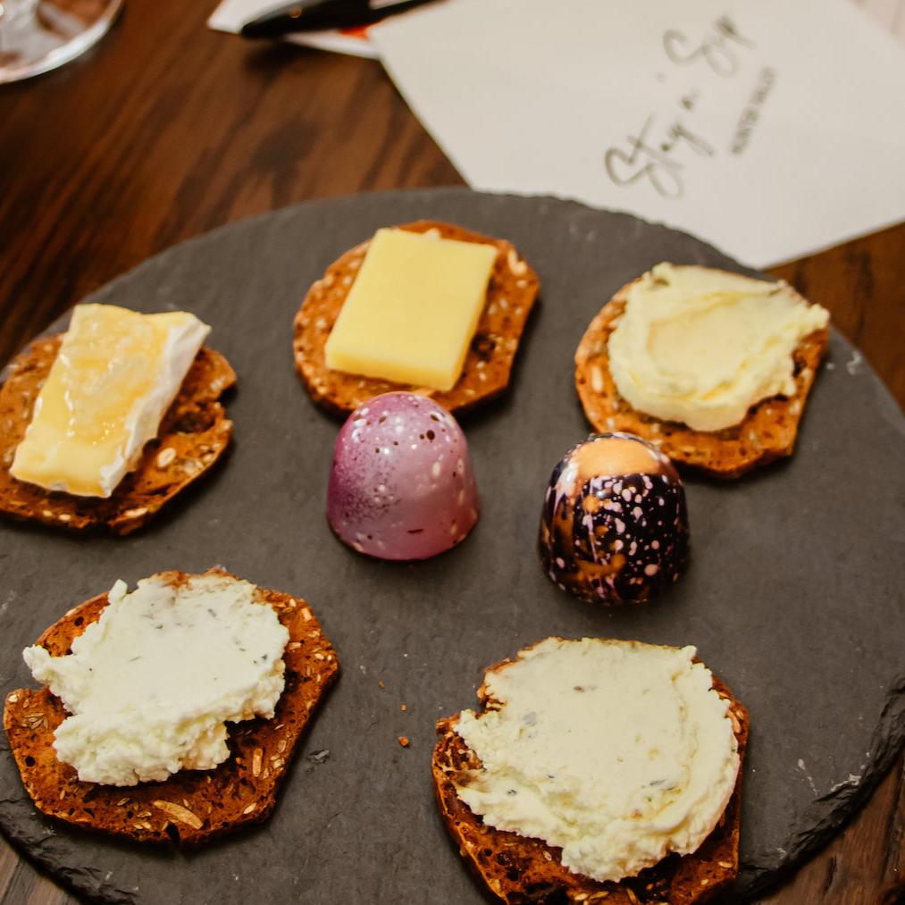 Gourmet cheese and chocolate pairing plate from Stay n’ Sip, featuring artisanal cheeses on crackers and handcrafted chocolates, enhancing the wine tasting experience with luxurious flavors