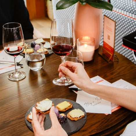 Guest enjoying a glass of red wine paired with gourmet cheese and crackers during a Stay n’ Sip Gourmet Wine Tasting, highlighting the refined and intimate tasting experience.