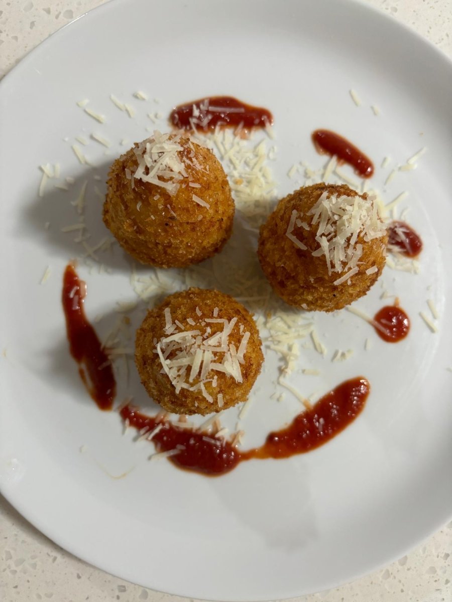 Golden, crispy arancini balls topped with grated Parmesan cheese, served with dollops of tangy tomato sauce on a white plate. A savory delight from Stay n' Sip's gourmet meal delivery service, perfect for pairing with Hunter Valley wines