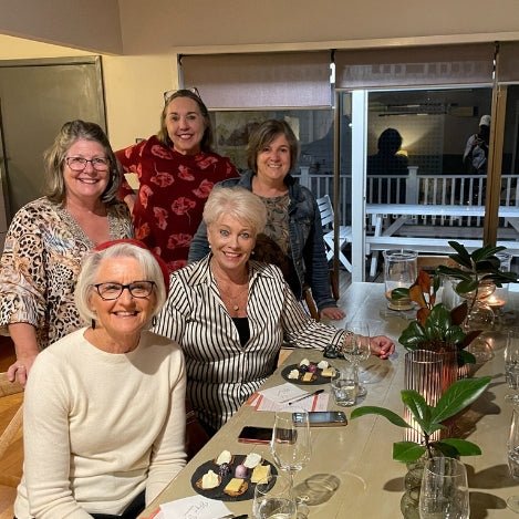 Group shot of guests facing the camera with table set for a wine tasting.