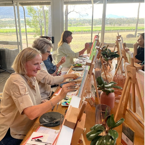 Group of guests painting and wine tasting.