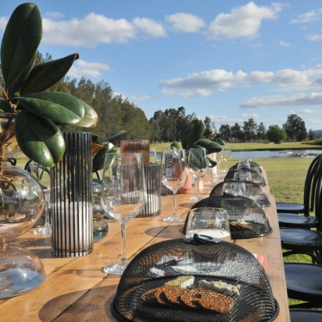 Long table overlooking a golf course set with tasting plates and wine glasses for a tasting experience in the sunshine.