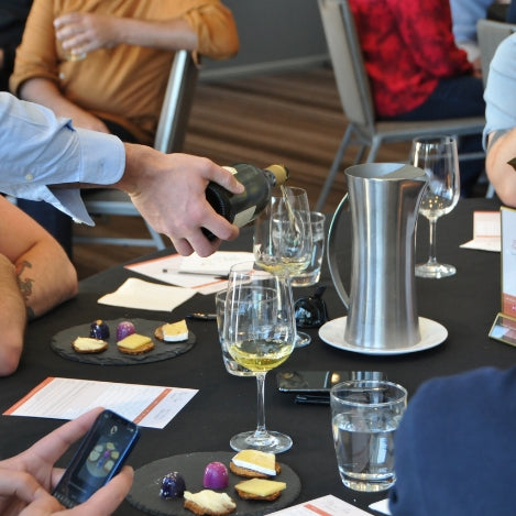 Wine being poured into a glass on a table with tasting plates.