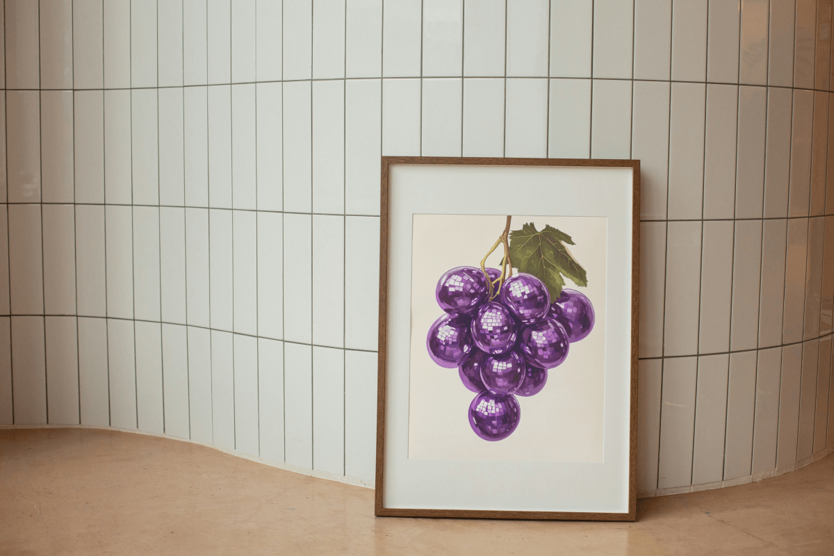 Framed Thirsty Merchy poster featuring a cluster of vibrant purple grapes with a reflective disco-ball effect and a green leaf, resting against a tiled wall. Part of Stay n' Sip's exclusive collection, this artwork celebrates Hunter Valley’s modern wine culture and is available for purchase online