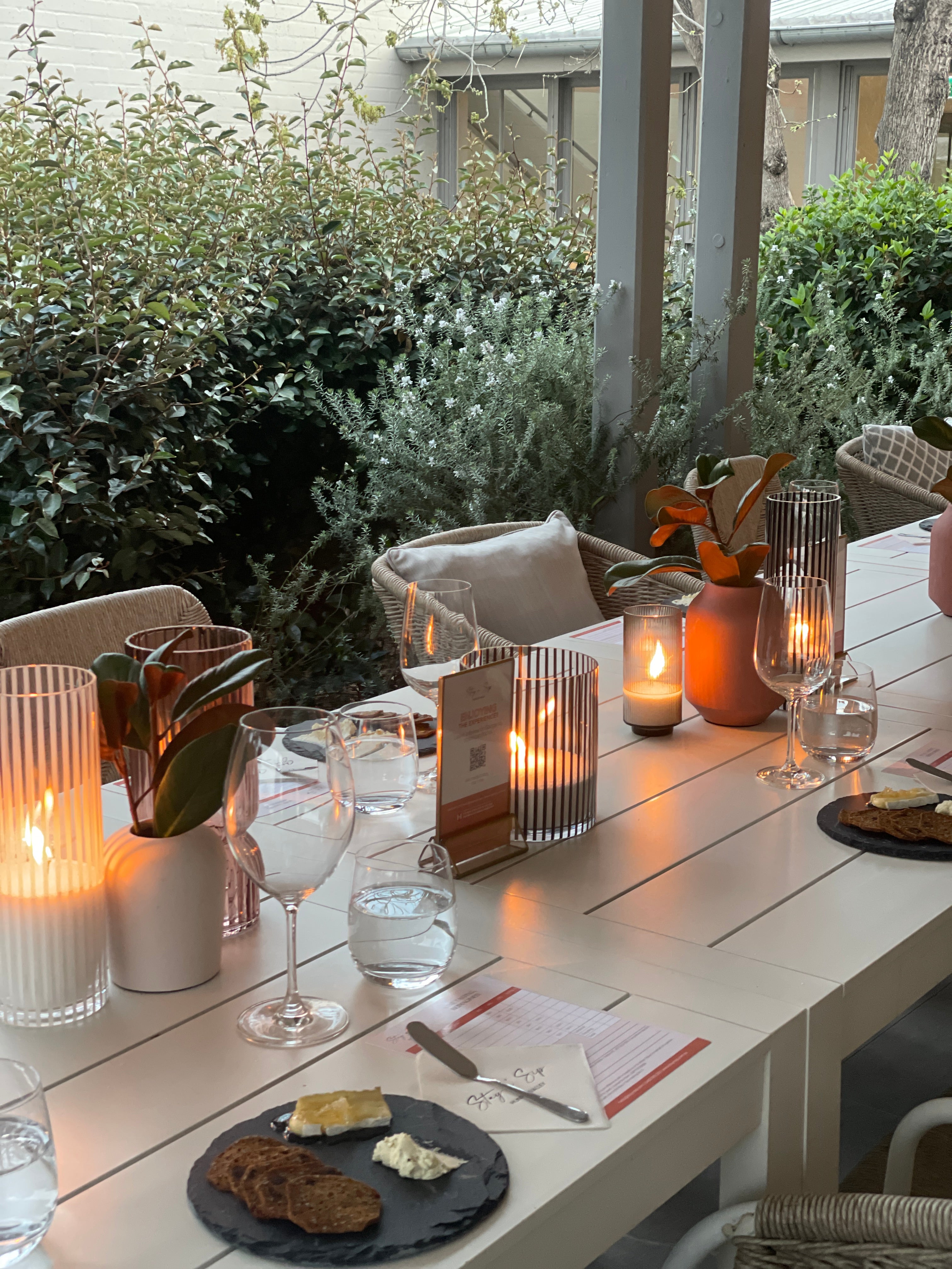 Long table overlooking a fabulous patio set with tasting plates and wine glasses for a tasting experience in the sun.