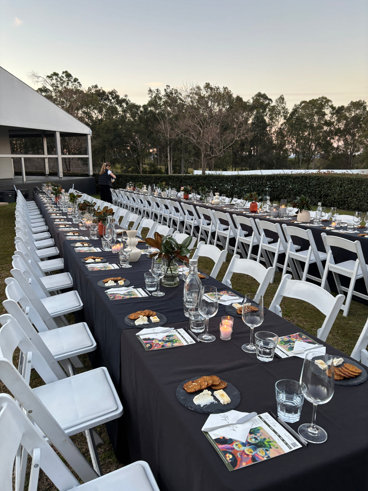 Outdoor sit down wine tasting event for 90 guests setup with tables, chairs, and cheese platters.