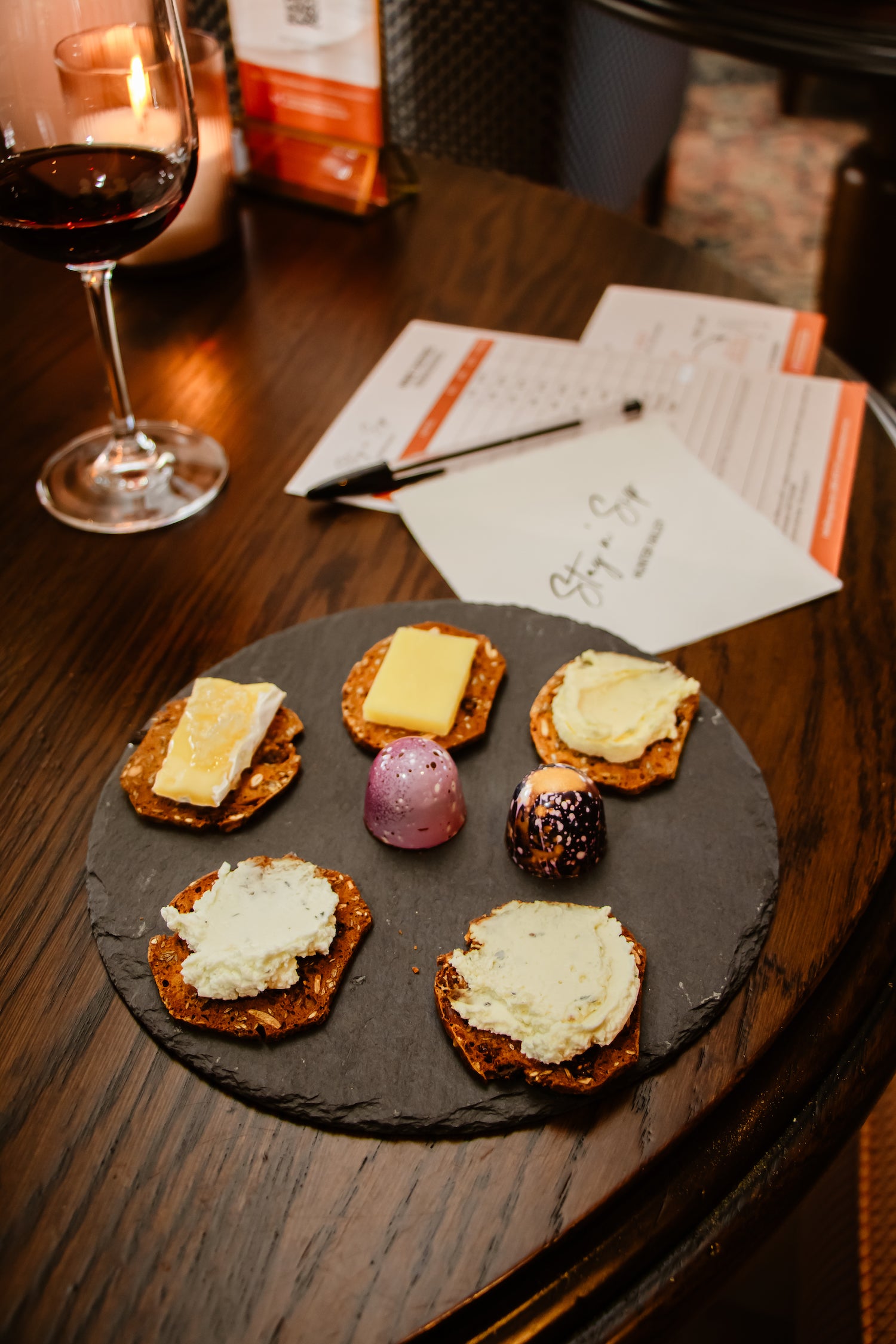 Slate with five different cheeses on gourmet crackers with two hand painted chocolate bon bons.