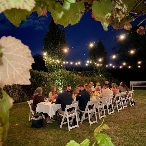 Long table with guests at night outside for a wine tasting experience.
