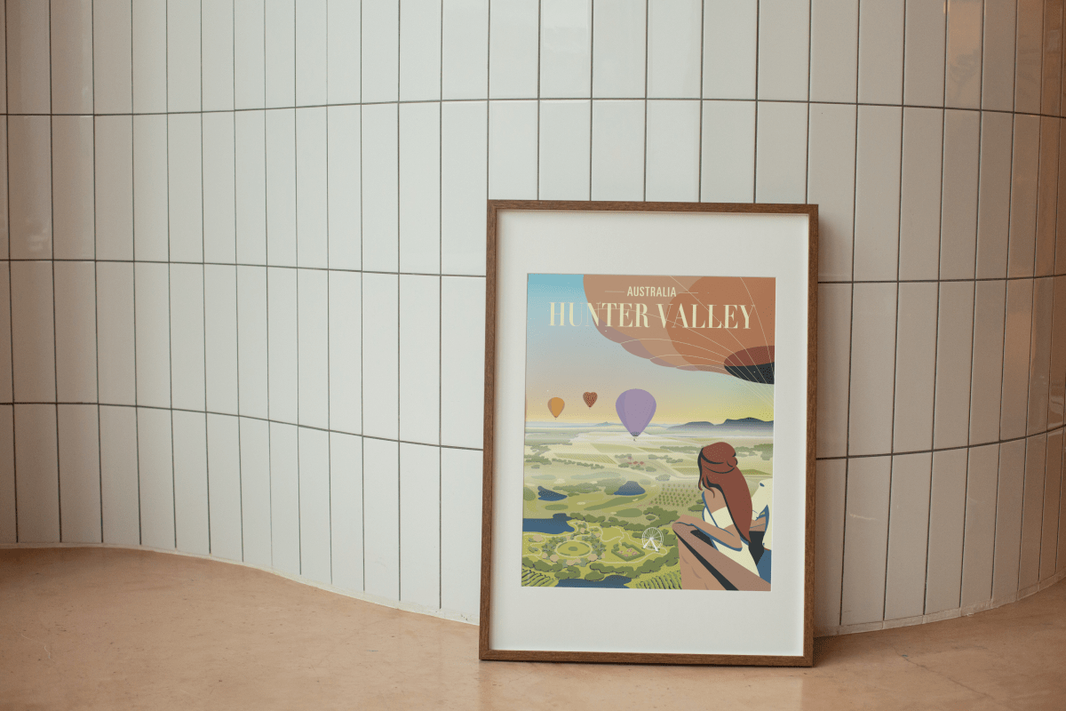 Framed Hunter Valley Balloon Sunrise Poster displayed against a modern tiled wall, showcasing an artistic view of hot air balloons floating over the scenic vineyards of Hunter Valley.